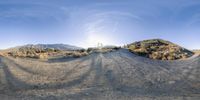 a view of a desert area with dirt roads and mountain views from the bottom, looking up at the sun