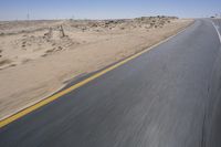 a person on a motorcycle rides down some road in the desert as it goes toward the camera