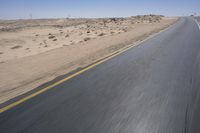 a person on a motorcycle rides down some road in the desert as it goes toward the camera