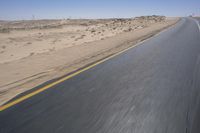 a person on a motorcycle rides down some road in the desert as it goes toward the camera