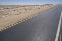 a person on a motorcycle rides down some road in the desert as it goes toward the camera