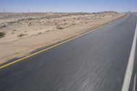 a person on a motorcycle rides down some road in the desert as it goes toward the camera