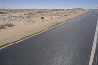 a person on a motorcycle rides down some road in the desert as it goes toward the camera