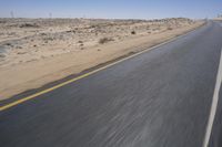 a person on a motorcycle rides down some road in the desert as it goes toward the camera