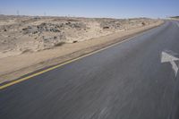 a person on a motorcycle rides down some road in the desert as it goes toward the camera