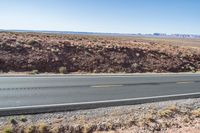 Desert Highway: Asphalt Road with Red Rock Surroundings