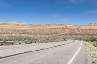 a curve of a highway with the mountains in the distance at the background that is dry and rocky
