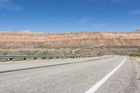 a curve of a highway with the mountains in the distance at the background that is dry and rocky