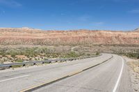 a curve of a highway with the mountains in the distance at the background that is dry and rocky