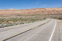 a curve of a highway with the mountains in the distance at the background that is dry and rocky
