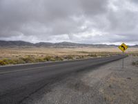 there is a small yellow sign on the side of the road near a large desert area