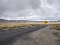 there is a small yellow sign on the side of the road near a large desert area