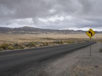 there is a small yellow sign on the side of the road near a large desert area