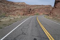 a person riding a motorcycle along a narrow road through rocks and sand cliffs a grassy area on both sides