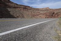 a person riding a motorcycle along a narrow road through rocks and sand cliffs a grassy area on both sides