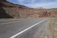 a person riding a motorcycle along a narrow road through rocks and sand cliffs a grassy area on both sides