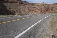 a person riding a motorcycle along a narrow road through rocks and sand cliffs a grassy area on both sides