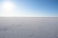 a person riding a horse on a snow covered field with sun shining on the horizon