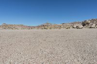 a rock - strewn field of rocks and dry grass under a bright blue sky with no clouds