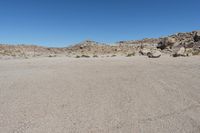 a rock - strewn field of rocks and dry grass under a bright blue sky with no clouds