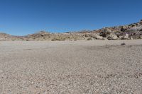 a rock - strewn field of rocks and dry grass under a bright blue sky with no clouds