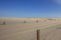 the road is covered in sand by barbed wire fences and water features on the side of the dirt road