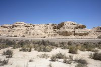 the desert landscape with sand and plants in it and rocks rising out from the hills