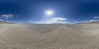 a desert landscape with a wide blue sky and mountains beyond it in the background, you can see an aerial 360 - angle view