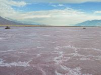 the desert has pink color, blue skies and clouds in it as if a storm