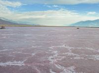 the desert has pink color, blue skies and clouds in it as if a storm