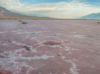 the desert has pink color, blue skies and clouds in it as if a storm