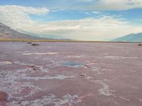 the desert has pink color, blue skies and clouds in it as if a storm