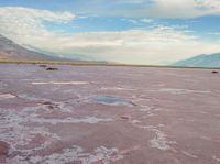 the desert has pink color, blue skies and clouds in it as if a storm