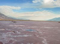 the desert has pink color, blue skies and clouds in it as if a storm