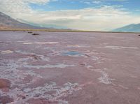 the desert has pink color, blue skies and clouds in it as if a storm