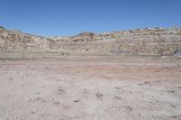 a dirt field in the middle of a desert mountainside with lots of sand and rocks