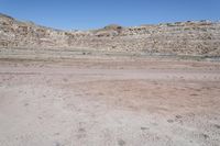 a dirt field in the middle of a desert mountainside with lots of sand and rocks