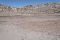 a dirt field in the middle of a desert mountainside with lots of sand and rocks