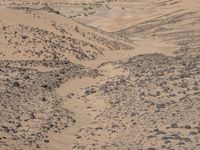 a truck on a dirt road in the desert with rocks and stones on the ground