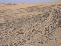 a truck on a dirt road in the desert with rocks and stones on the ground