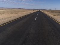 an empty street that is connected to a dry area near the horizon in the desert