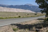 a desert landscape with a motorcycle parked on it next to a mountain range and an empty highway