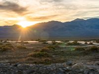 the setting sun and mountain range in a deserted landscape along the colorado river, with mountains covered in snow