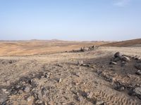 a truck on a dirt road in the desert with rocks and stones on the ground