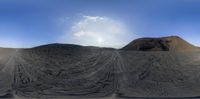 a desert area with dirt and sand on the ground and blue sky above it in a panorama lens