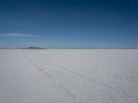 a car driving across a large open plain covered in snow on a sunny day by itself