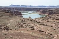 a desert area that has a river and a few hills in the background and a large body of water