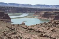 a desert area that has a river and a few hills in the background and a large body of water