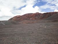 a person riding their horse on a very barren desert land area as clouds hove in