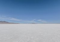 a barren area with mountains in the background and no clouds in the sky, with only one person visible